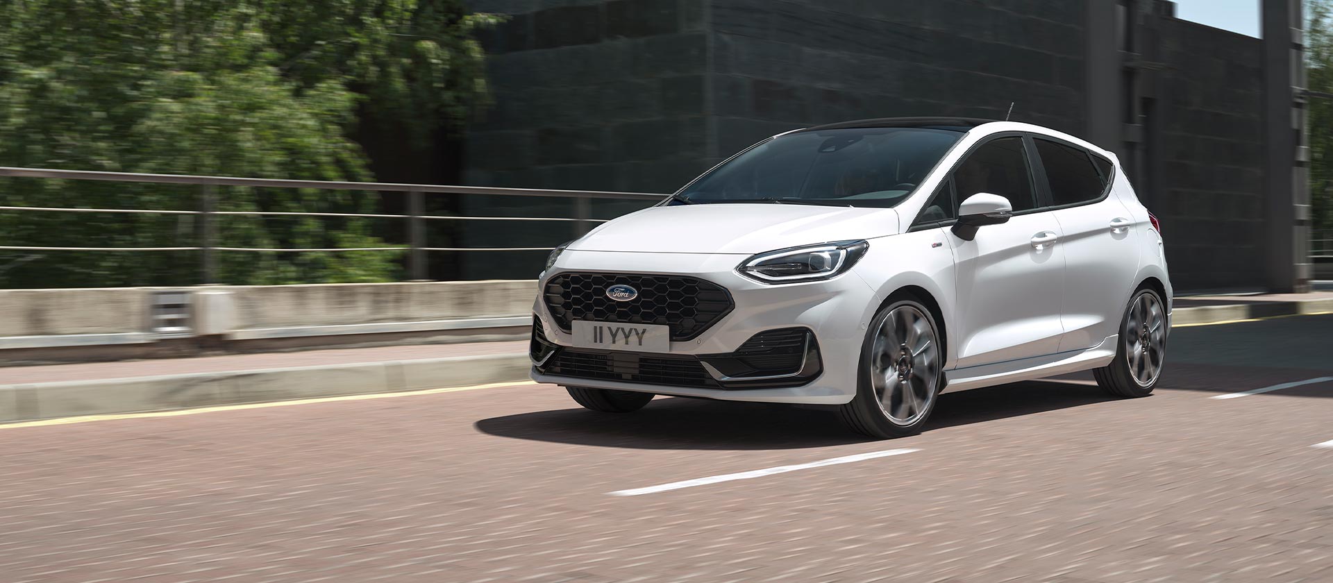 Ford Fiesta branco a conduzir numa cidade.