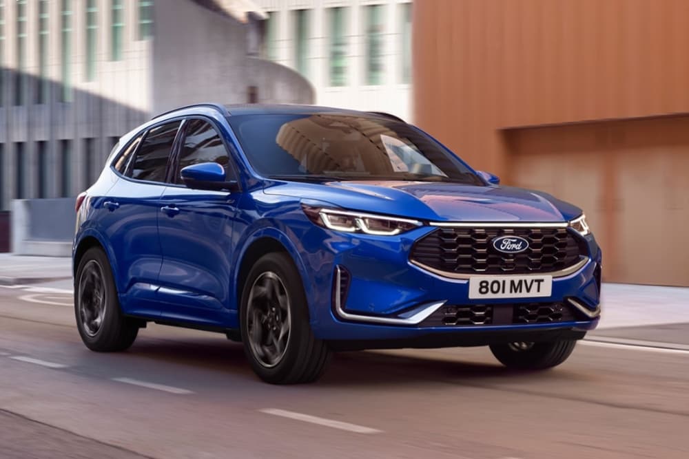 Um SUV híbrido plug-in Ford Kuga azul estacionado numa estrada cénica de montanha.