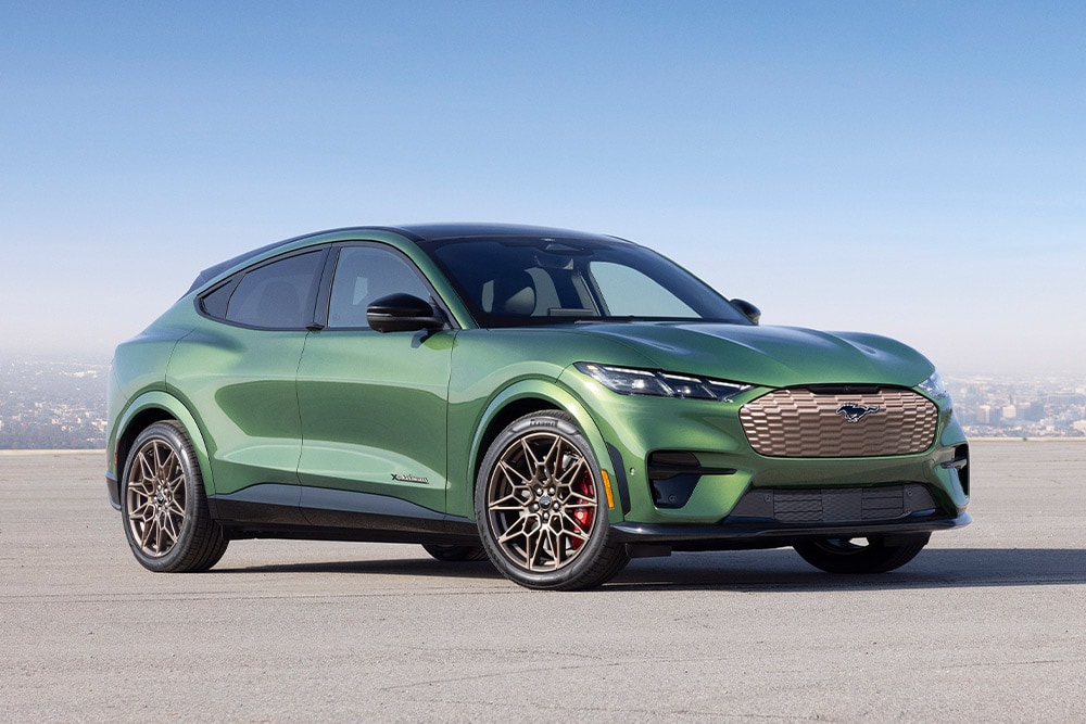 Um Ford Mustang Mach-E verde estacionado em frente ao horizonte da cidade.