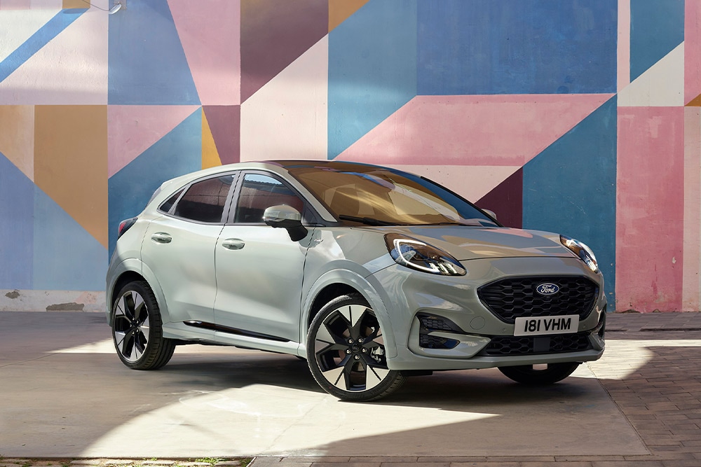 Um Ford Puma SUV prateado estacionado em frente a um mural geométrico colorido.