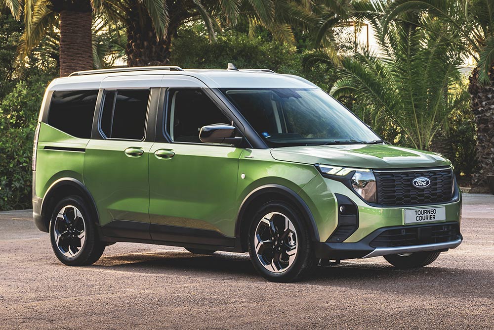 Uma carrinha Ford Tourneo Courier verde estacionada no exterior de um edifício de escritórios.