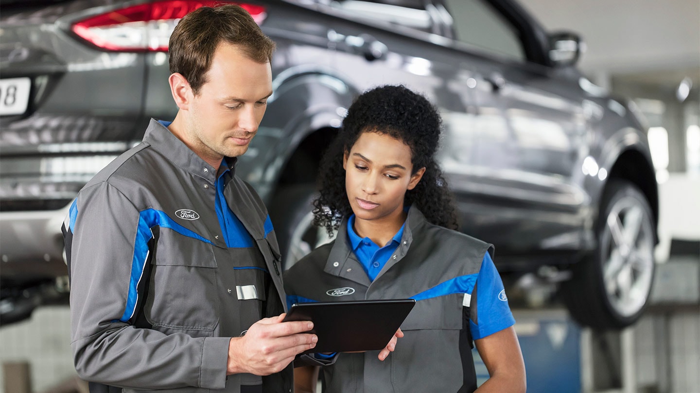 Dois especialistas em reparação da Ford analisam o seu sistema de reserva de serviços online num telefone.