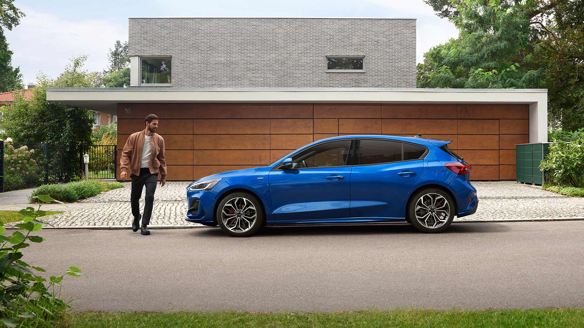 Homem a aproximar-se de um Ford Focus azul estacionado em frente a uma casa
