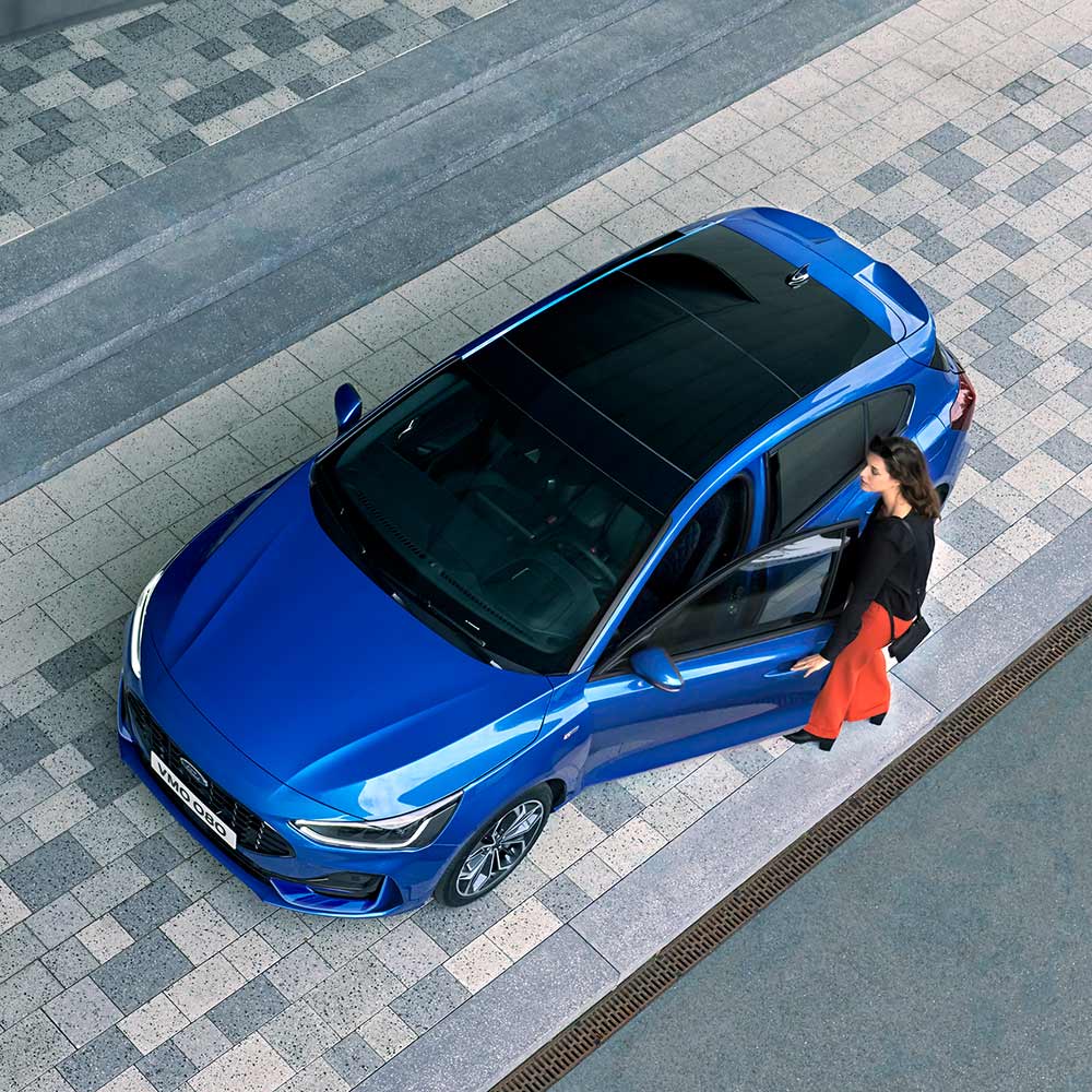 1000x1000 image of a Blue Focus parked on a main road.