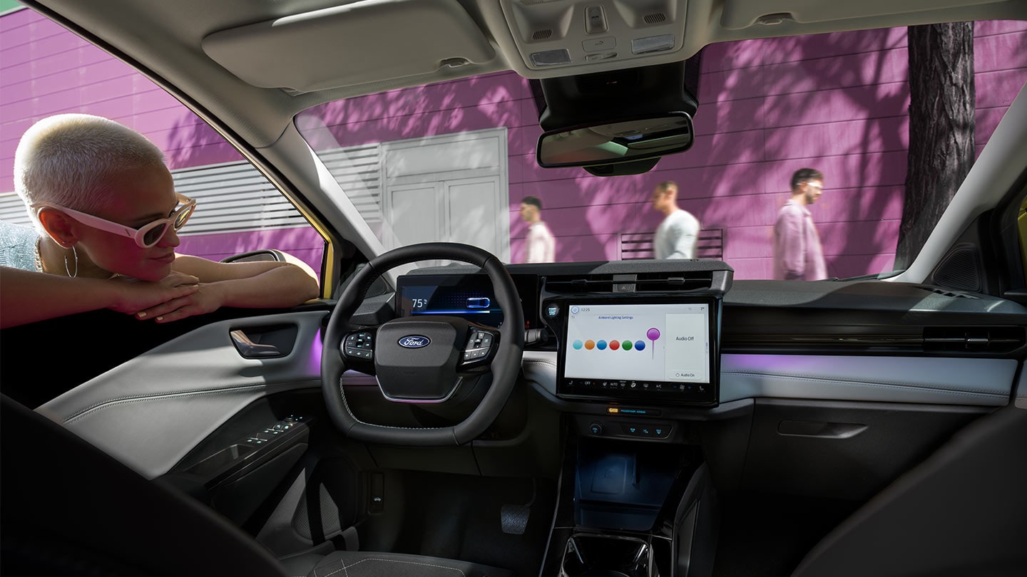 Pessoa a olhar para o interior do novo Ford Puma Gen-E®, mostrando o grande ecrã tátil e a iluminação ambiente.