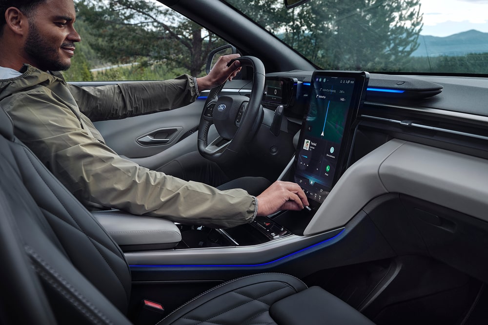 Condutor a utilizar o sistema de infoentretenimento no ecrã tátil do SUV familiar Ford Explorer.