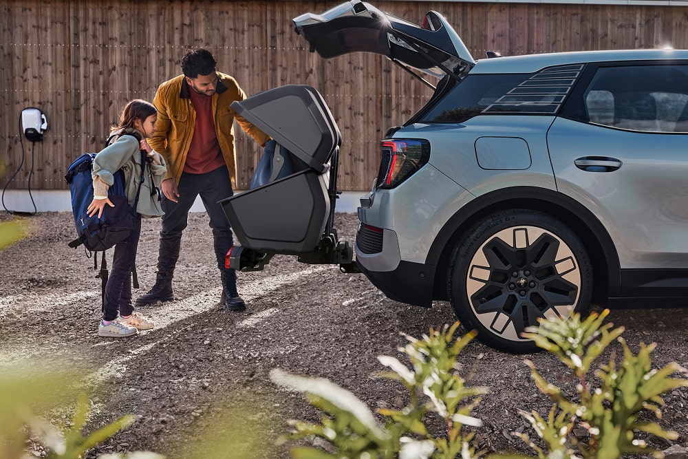 Homem e criança a carregar carrinho de bebé na bagageira do Ford Explorer, SUV familiar.